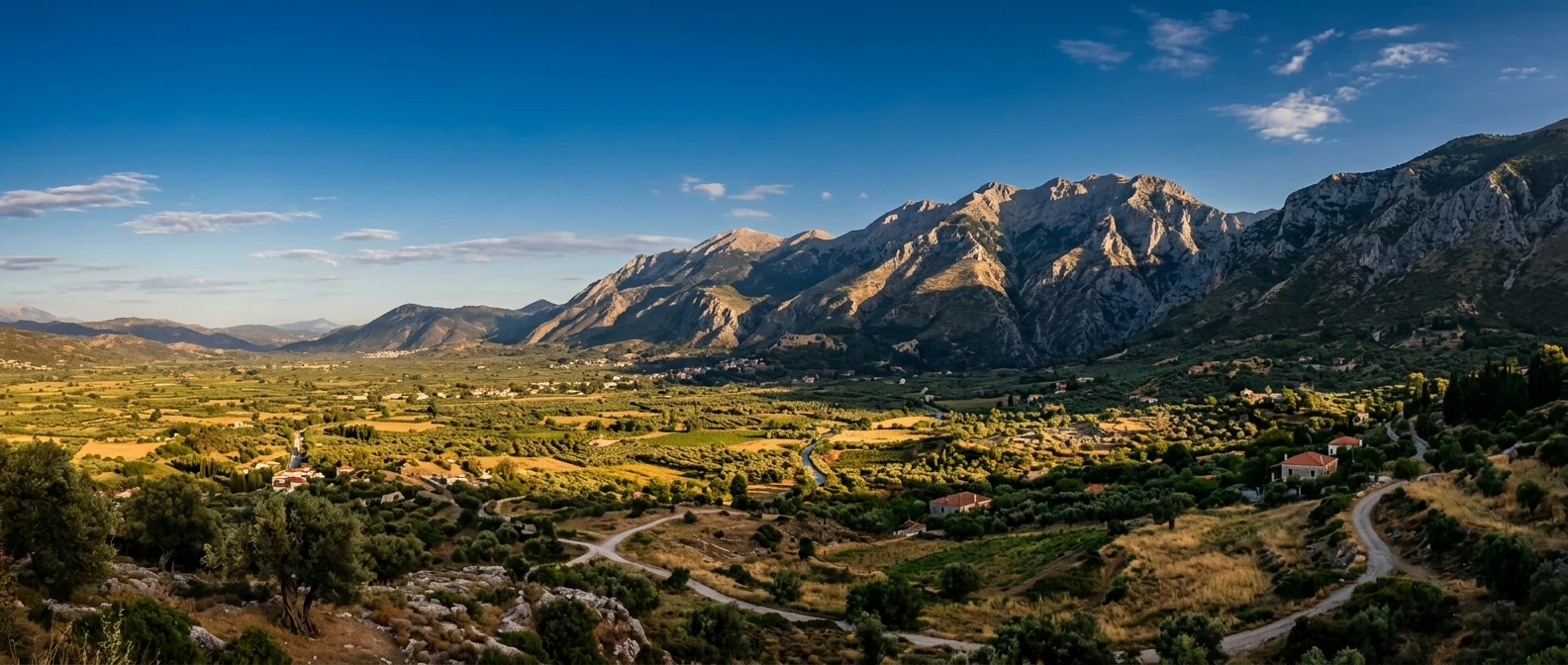 Τα βουνά της Λακωνίας και η πεδιάδα της Σπάρτης σε χαμηλό απογευματινό φως, με ερείπια στο βάθος