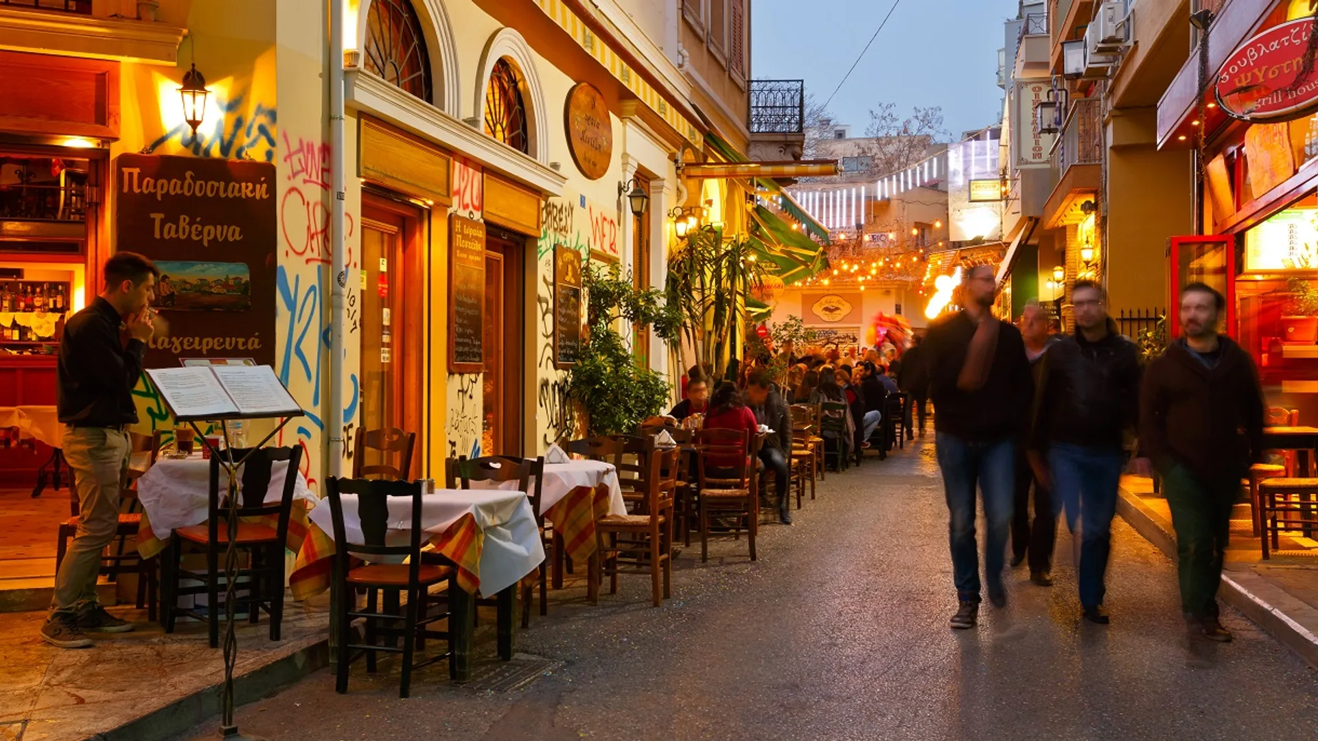Στενό δρομάκι του Ψυρρή με μπαρ και τραπέζια στο πεζοδρόμιο τη νύχτα